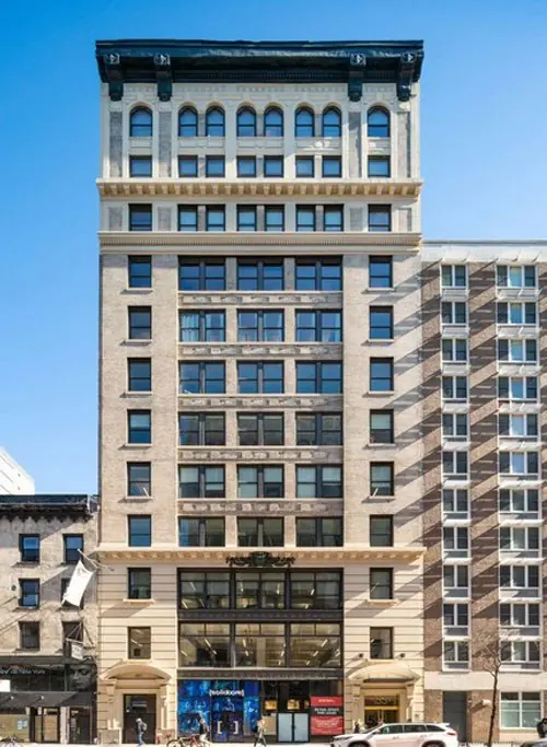 155 West 23rd Street, a tan-brick and limestone tower with arched windows under a dark cornice