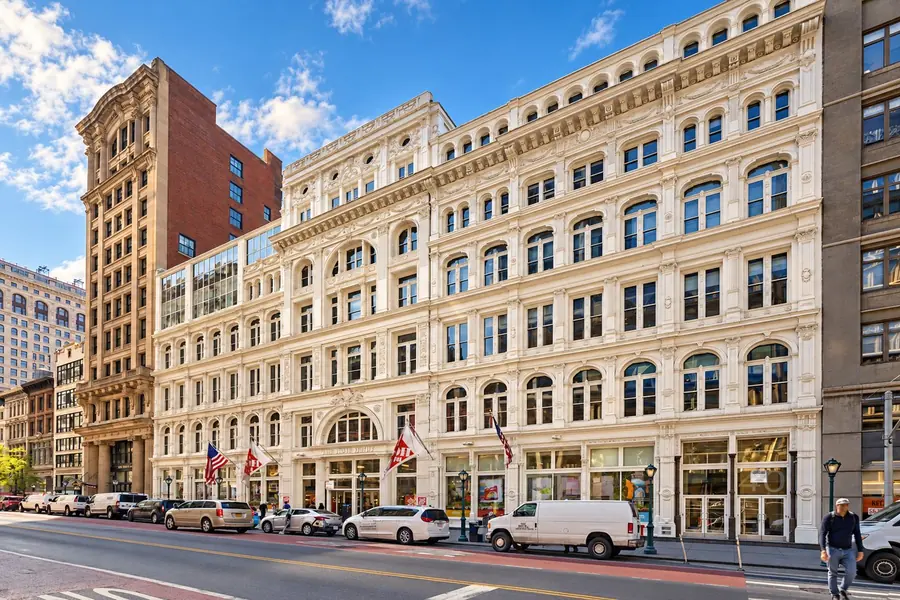 28 West 23rd Street, a cream-colored cast-iron building with arched windows and flags above the entrance